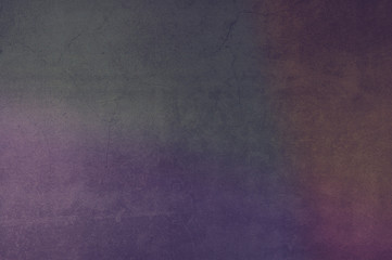 Background wall of aged textured aged plaster with stains of purple green and yellow.