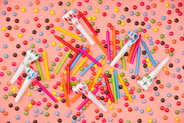 Colorful sprinkles, blowers and birthday candles on pink backgro