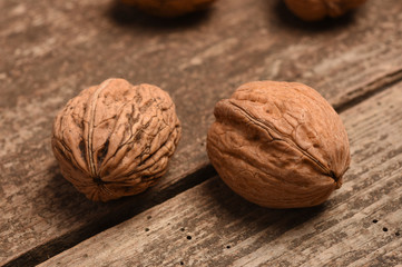 Walnut kernels and whole walnuts on rustic old oak table.
