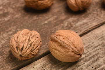 Walnut kernels and whole walnuts on rustic old oak table.
