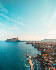 Beautiful mediterranian coastline near Calpe, Spain with small town, hotels, buildings and roads. Summer autumn blue turquoise sea water and warm colors coastline. Aerial drone shot view