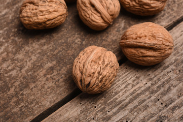 Walnut kernels and whole walnuts on rustic old oak table.