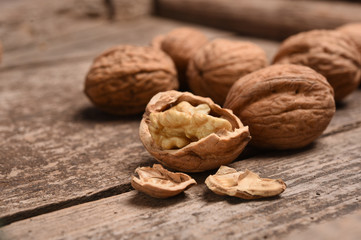 Walnut kernels and whole walnuts on rustic old oak table.