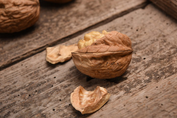 Walnut kernels and whole walnuts on rustic old oak table.