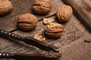 Walnut kernels and whole walnuts on rustic old oak table.