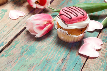 Tasty cupcake with tulips on vintage wooden table with copy space. Romantic love background.