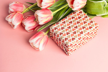 Romantic background with tulips and gift box on pink pastel background.
