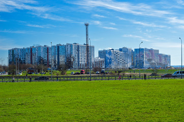 Green lawn and modern apartment buildings. City skyline. Walking zone, comfortable residential quarters. Sunny spring weather. St. Petersburg, Russia, 1 May 2018