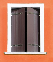 rectangular window with closed shutters and orange wall