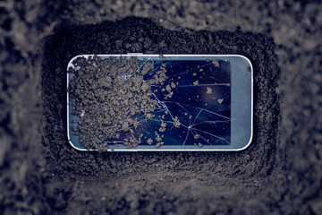 Mobile phone with broken glass in the grave. Burial of a spoiled phone. Mourning_