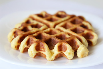 Belgian waffles in white plate. Healthy breakfast close up, freshly baked classic wafer