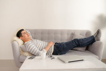 Asian guy daydreaming and rest at home. Asian man relaxed and sleep on sofa indoor. Handsome male model.