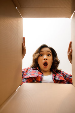 Smiling young woman opening a carton box, relocation and unpacking concept