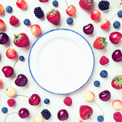 Fototapeta na wymiar Berry food frame with empty white plate in the middle.
