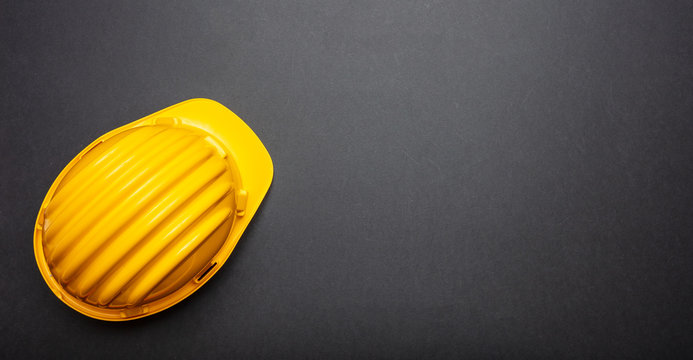 Construction project safety, Yellow hard hat on black color background, copy space