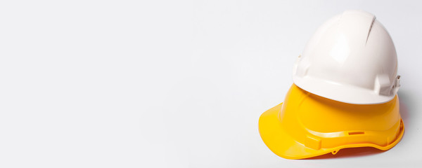 Yellow and white protection helmets isolated on white. Construction site engineer and worker head safety horizontal background with empty copy space.