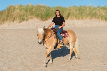 girl riding on haflinger horse on th beach