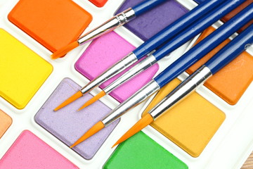 Set of solid watercolors and paintbrush on wooden table background