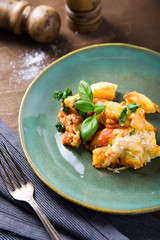 Italian food. Gnocchi with cheese and basil in handmade on a green plate on the old wooden table, near the vintage fork and knife.