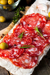 Chorizo sausage and salami, thin cut. spanish salami on the wood background with spices, paprika, pepper. Spicy food. Chili.