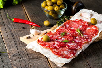 Chorizo sausage and salami, thin cut. spanish salami on the wood background with spices, paprika, pepper. Spicy food. Chili.