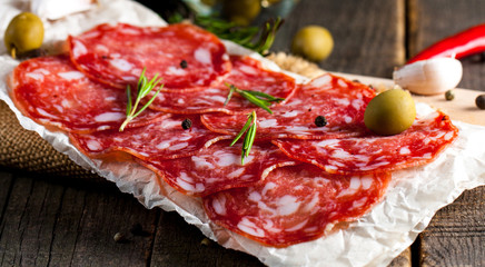 Chorizo sausage and salami, thin cut. spanish salami on the wood background with spices, paprika, pepper. Spicy food. Chili.