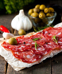 Chorizo sausage and salami, thin cut. spanish salami on the wood background with spices, paprika, pepper. Spicy food. Chili.