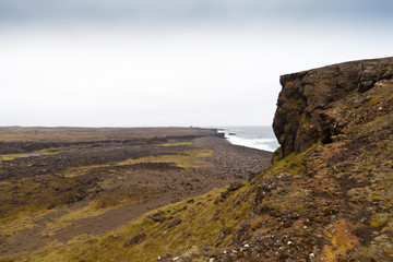 Rocky cliff with grass on Iceland Reykjanes peninsula volcanic stones shore coast line
