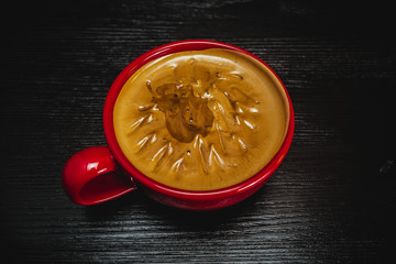 fresh aromatic coffee in a red mug on a black wooden background