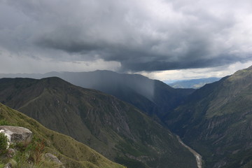 山頂から遠くに雨と晴れの切れ目を見る