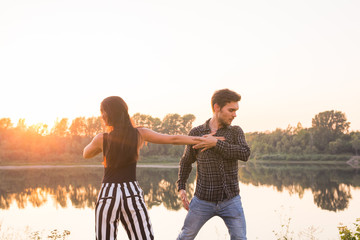 Romantic, social dance and people concept - young couple dancing a tango or bachata near the lake