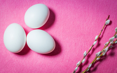 Easter eggs and blooming willow branches on a pink background