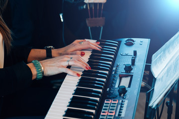 Female musician playing on piano keys of synthesizer