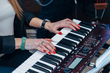 Female musician playing on piano keys of synthesizer