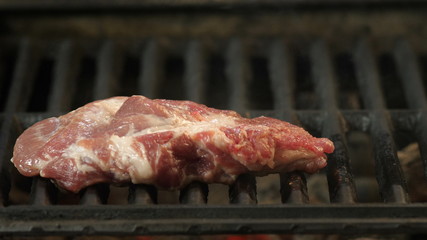 The chef cooks a large piece of steak, beef, lamb, pork, veal, the cooking process, slow-motion shooting, close-up video on the rosette grill with a swirling smoke