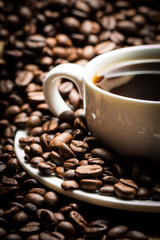 Coffee cup and beans on a rustic background. Coffee Espresso and a piece of cake with a curl. Cup of Coffee and coffee beans on table