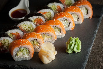 Maki rolls and nigiri sushi on a wooden table. Salmon, avocado and caviar rolls.