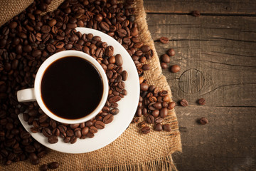 Coffee cup and beans on a rustic background. Coffee Espresso and a piece of cake with a curl. Cup of Coffee and coffee beans on table.