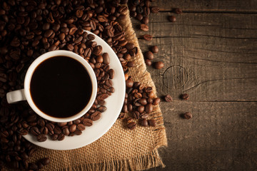Coffee cup and beans on a rustic background. Coffee Espresso and a piece of cake with a curl. Cup of Coffee and coffee beans on table.