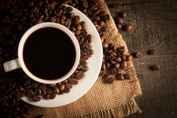 Coffee cup and beans on a rustic background. Coffee Espresso and a piece of cake with a curl. Cup of Coffee and coffee beans on table.
