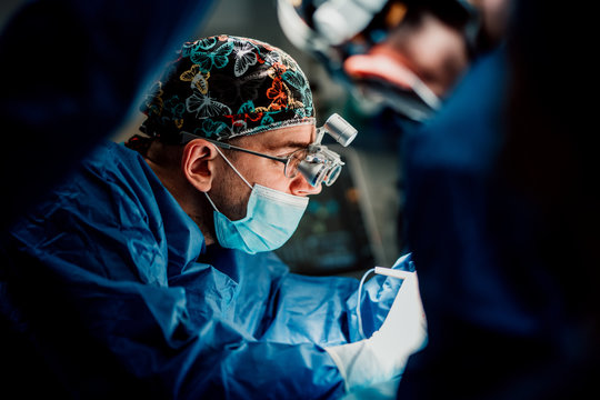 Professional caucasian male surgeon doctor performing invasive surgery in hospital room