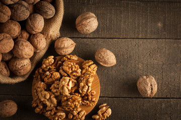 Walnut kernels in sack and whole walnuts on rustic old wood.