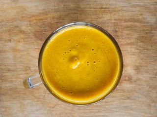 Top view on a glass of pumpkin smoothie beverage standings on a wooden surface