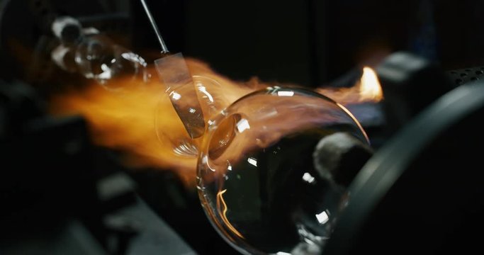 Slow motion macro of glass blower working with flame on a handmade art piece of glass from precious crystal in a workshop. Shot in 8K. Concept of handmade, quality, artisan, made in Italy, glass blow