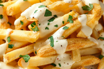 Homemade Baked Potato Fries with cheese sauce on white wooden board. closeup