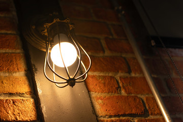 Antique electronic lamp, hanging at the red brick wall in the building.soft focus.