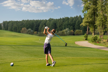 Boy playing golf, makigng shot from the tee