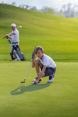 Boy playing golf, makigng shot on the green