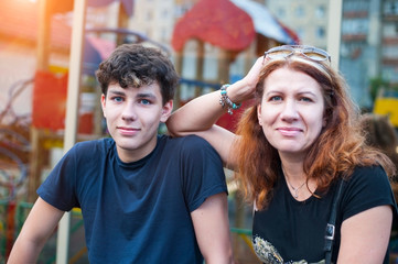 A beautiful woman with a teenage son resting in the summer in the city, happy because they resolved...
