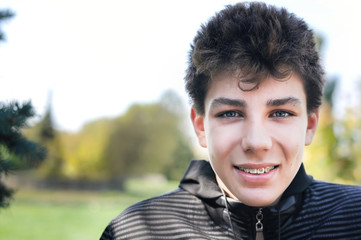 A beautiful teenager relaxes in the park in the spring and smiles. On the teeth, a boy has braces